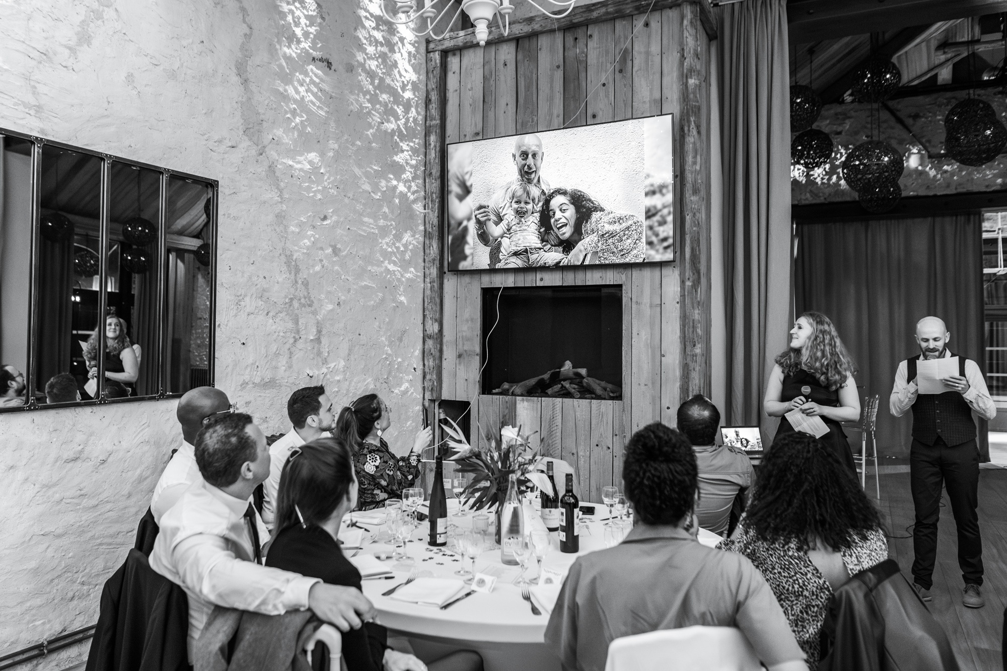 Photographe mariage au Clos de l'Orangerie à Rosny-sur-Seine - Reportage photo des invités pendant une projection lors de la réception.
