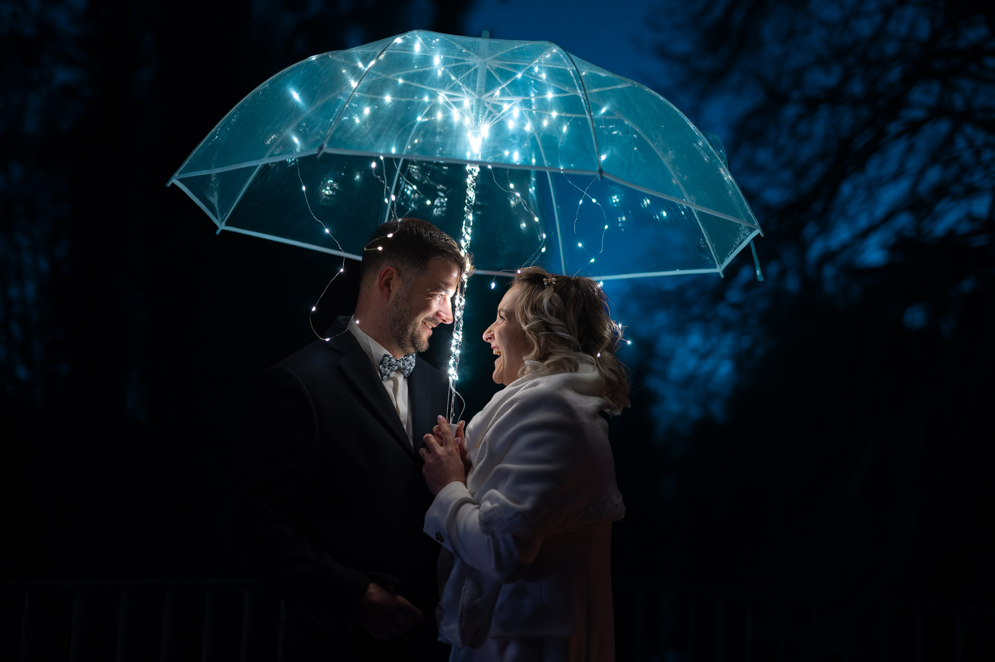 Photographe mariage Moulin de Lambouray - Portrait de nuit créatif des mariés sous un parapluie illuminé de guirlandes LED